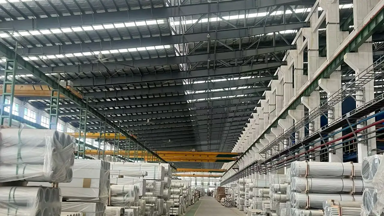 Extrusion hall with overhead cranes and wrapped profile bundles stacked along the aisle