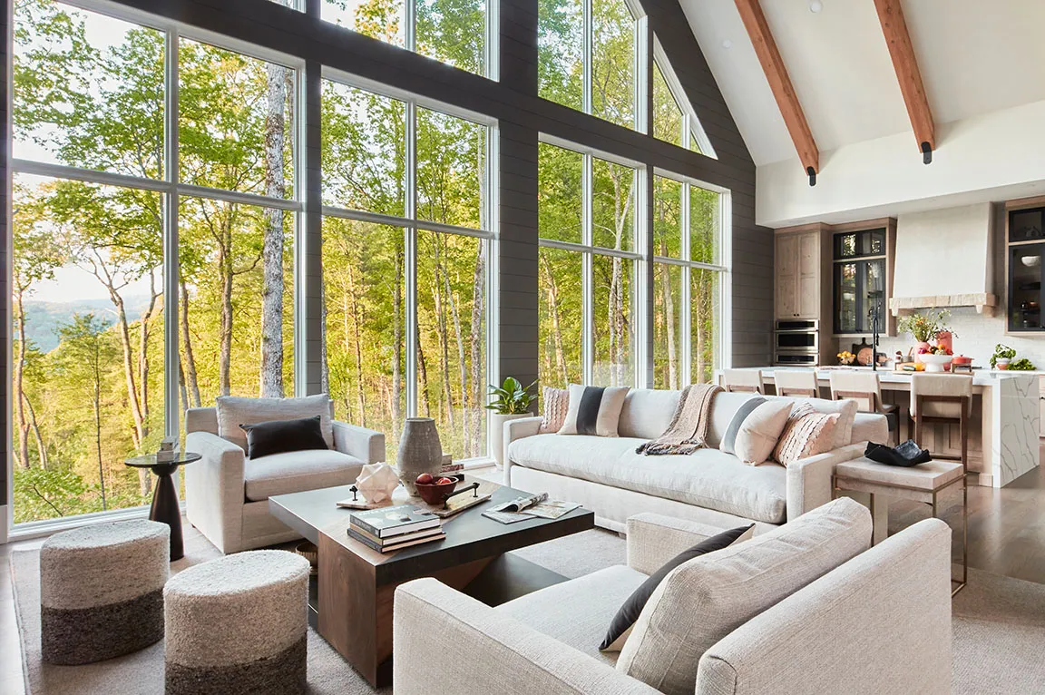 Living room with a full-height glazed gable wall in a forest setting